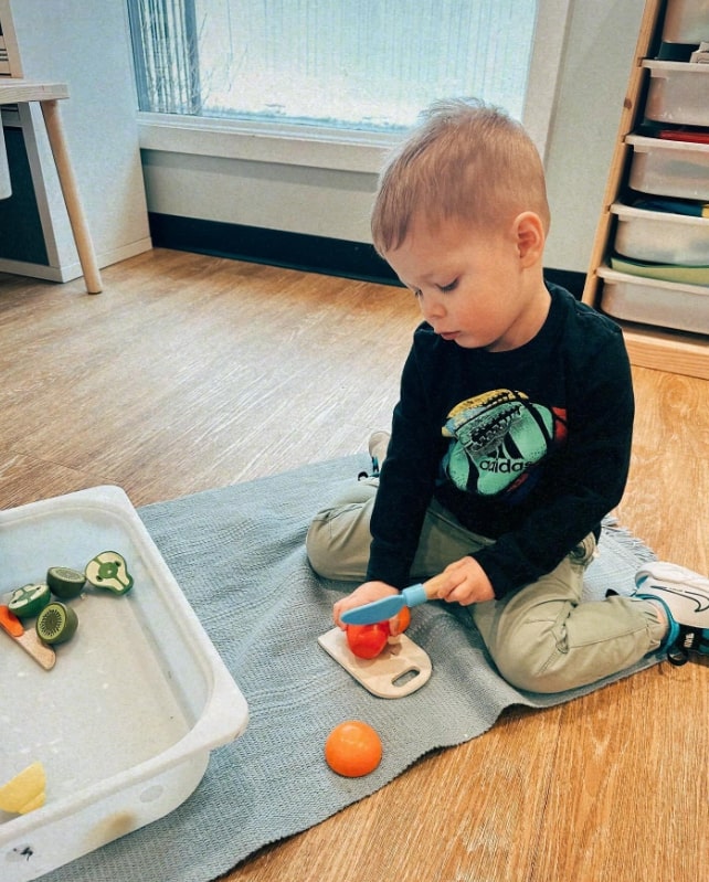 Student exploring cutting fruit with Montessori materials